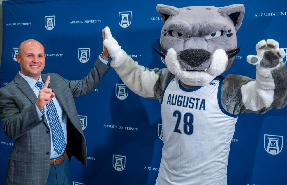 Man in suit gives mascot high five