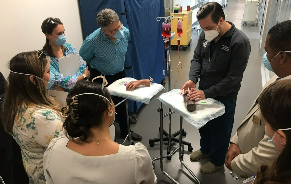 Simulation Center Director Justin Owen shows a team from U.S. Representative Rick Allen's office how to start an IV line.