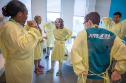 six volunteers dress in yellow hospital gowns