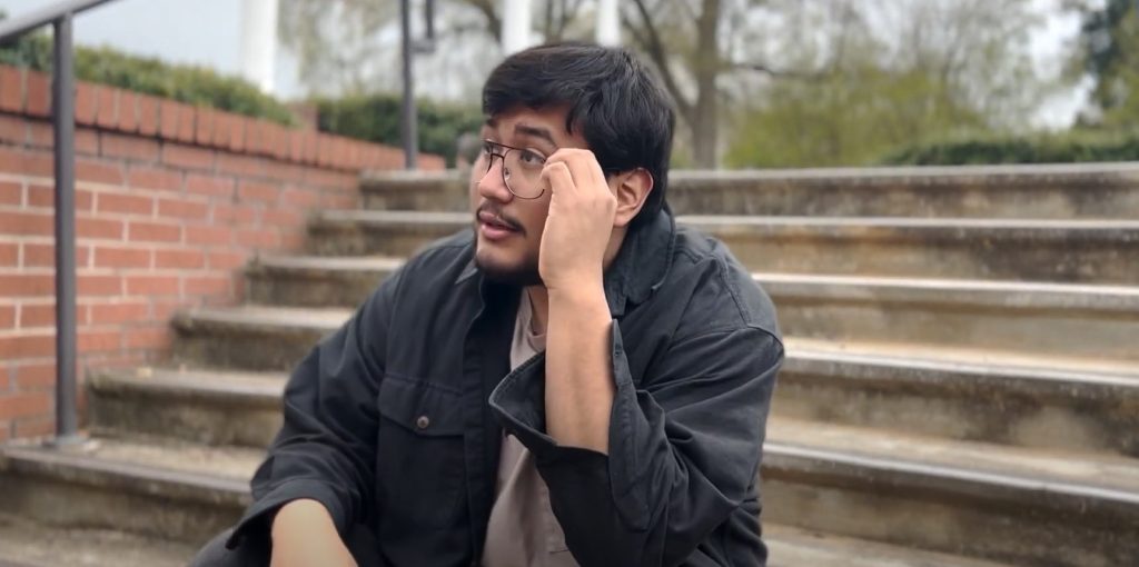In a screenshot from a PSA, a student is sitting on steps looking contemplative.