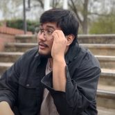 In a screenshot from a PSA, a student is sitting on steps looking contemplative.