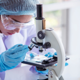 An epidemiologist conducts research using a microscope.