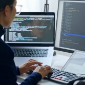 A database manager reviews code on a pair of monitors.