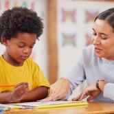 An elementary school teacher works with a student.