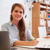 A teacher sitting at a desk and writing notes on a piece of paper.