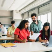 A teacher works with a student in a high school classroom.