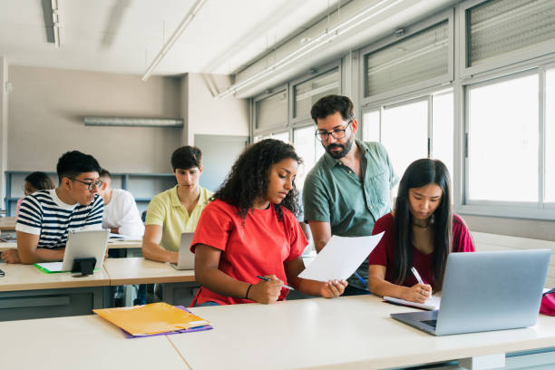 A teacher works with a student in a high school classroom.