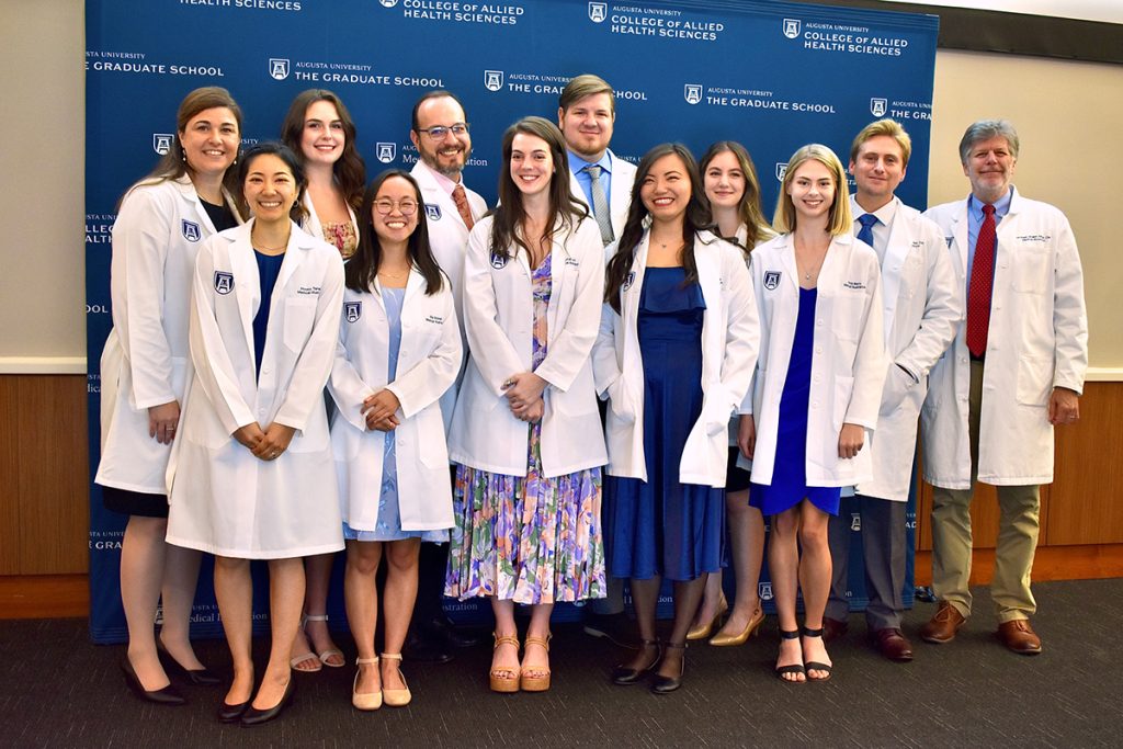 The Class of 2024 and faculty in their white coats.