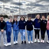College of Nursing students and Dr. Carol Hunter pose together in parking lot on cloudy day