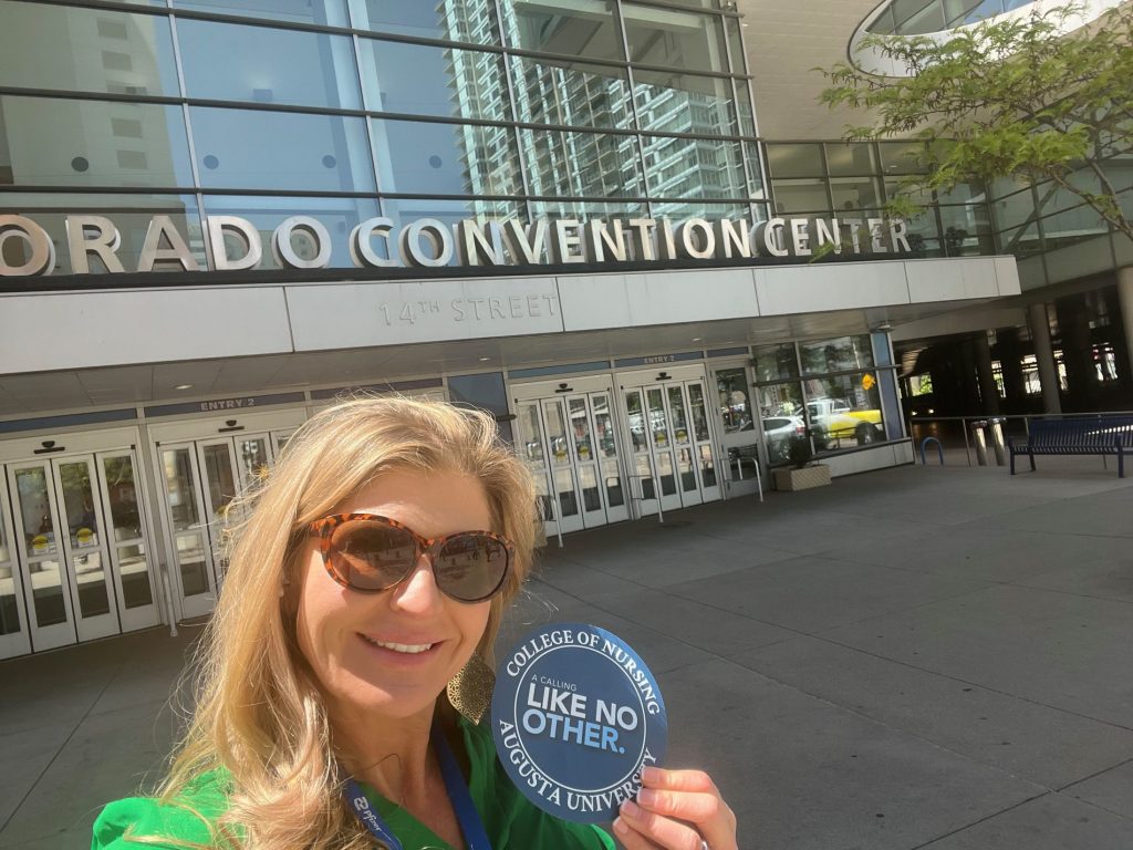 Dr. Jennifer Broxton posing with CON magnet outside Colorado Convention Center