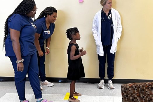 Local child is guided through eye test by Nurse Practitioner students