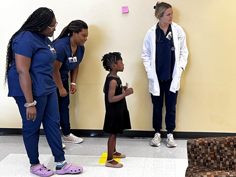 Local child is guided through eye test by Nurse Practitioner students