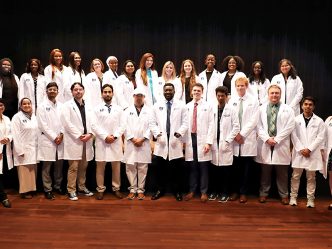 Group photo of students in white coats