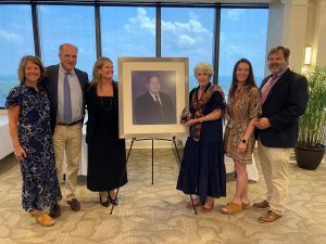 The family of co-founder Robert Crumrine posing with his portrait