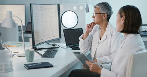 Two clinical data analysts reviewing data on a computer screen.