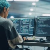 A cryptographer sits at a desk working on a desktop computer.