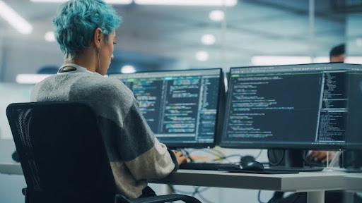 A cryptographer sits at a desk working on a desktop computer.