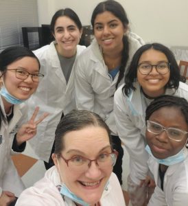 Dr. Langley-Brady poses with her 5 students, all dressed in lab coats