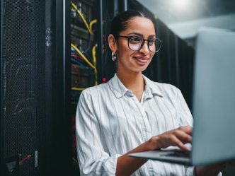 A security architect working on a laptop in a server room.