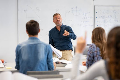 A high school teacher calls on a student in a classroom.