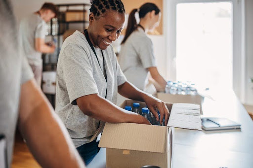 Community volunteers pack water bottles into cardboard boxes.