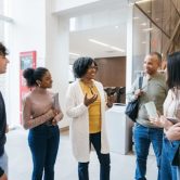 An education administrator meets with a group of teachers in a school hallway.