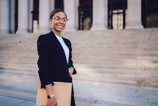 A public administration professional holding a folder stands outside of a government building.