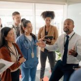 A public health manager addresses a group of health care and business professionals.