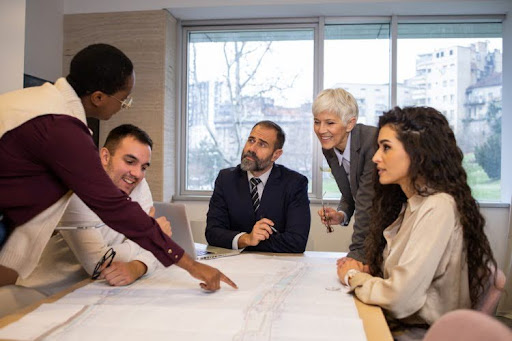 A city manager points to a map during a council meeting around a conference table.