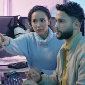 Two cybersecurity professionals work on computers and evaluate a cyber threat.