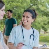 A public health nurse meets with a patient at an outdoor community health event.