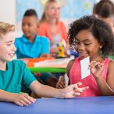 Two kindergarten students play a card game in a classroom.
