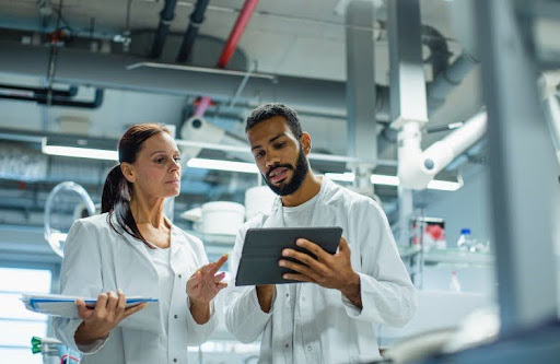Two epidemiologists in a laboratory look at a tablet.