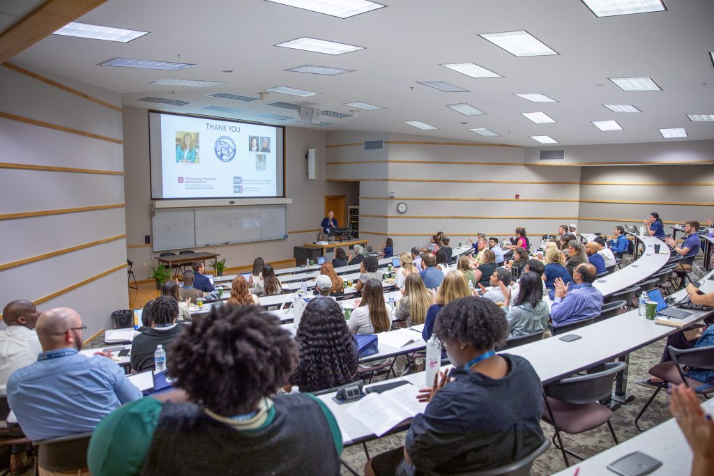 a lecture hall filled with people listening to a speaker