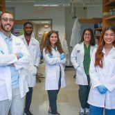 six students standing in white coats