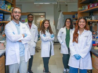 six students standing in white coats