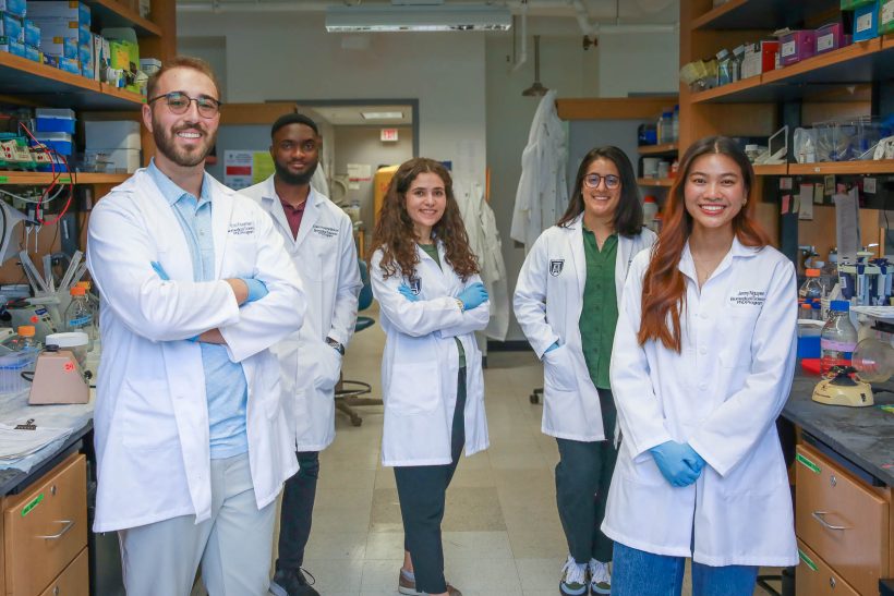 six students standing in white coats