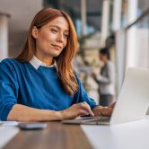 A business professional works on a laptop in an office.