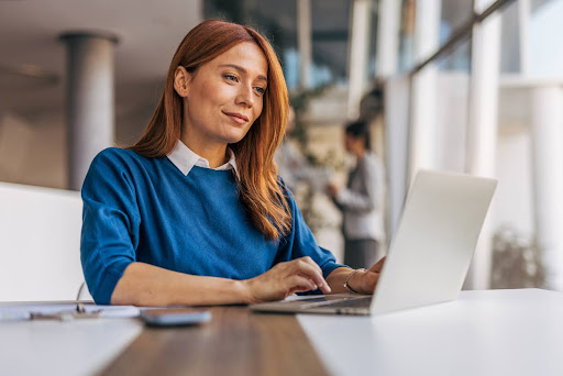 A business professional works on a laptop in an office.