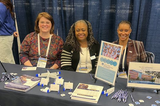 Representatives from the DCG smile while sitting at a recruiting table.
