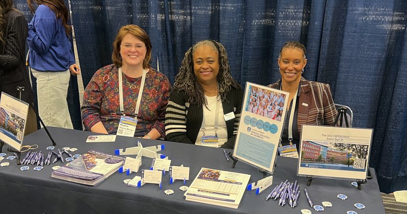 Representatives from the DCG smile while sitting at a recruiting table.