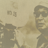 An old fashioned photograph of a man holding a vintage film camera