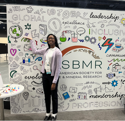 Jaeshia Londsay smiling in front of colorful photo brackdrop