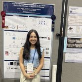 Student smiles in front of their research presentation