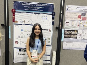 Student smiles in front of their research presentation