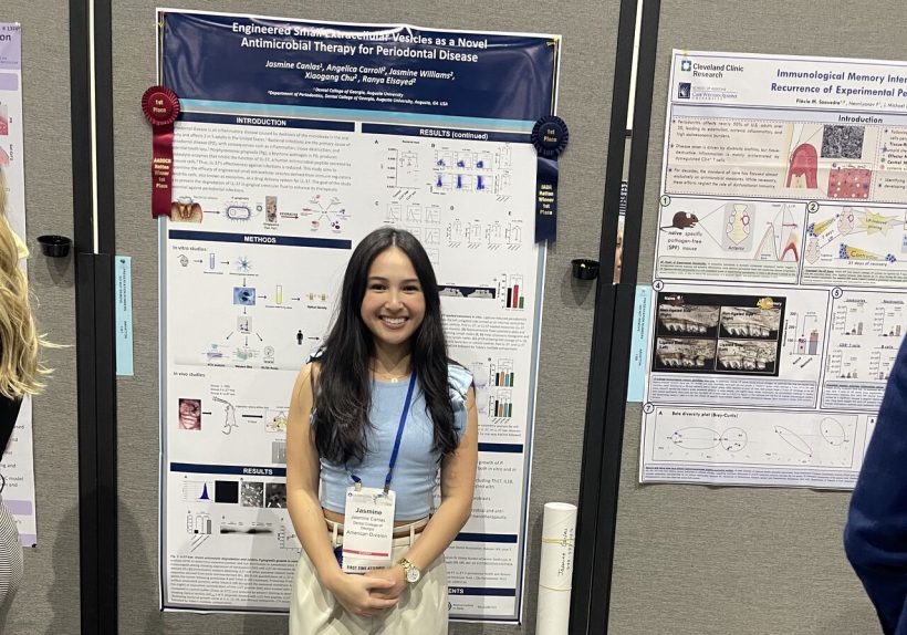 Student smiles in front of their research presentation