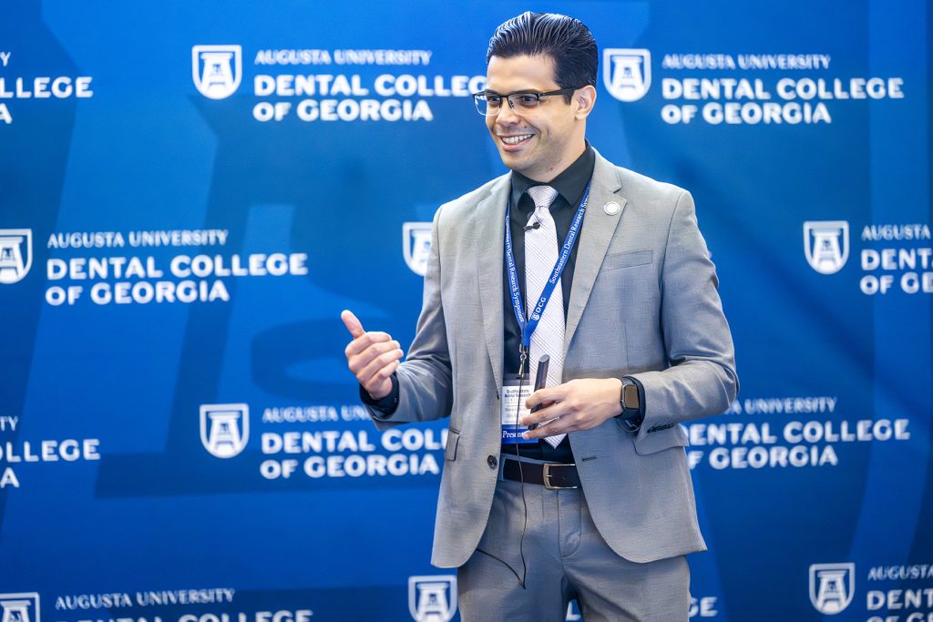 Presenter smiles and gives a thumbs up.