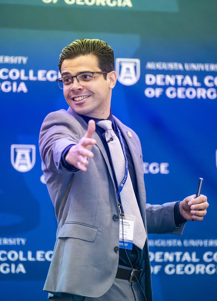 Presenter smiles and gestures to audience.