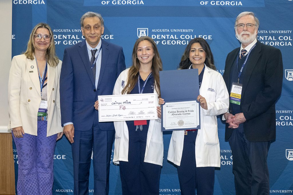 Winners hold award next to presenters.