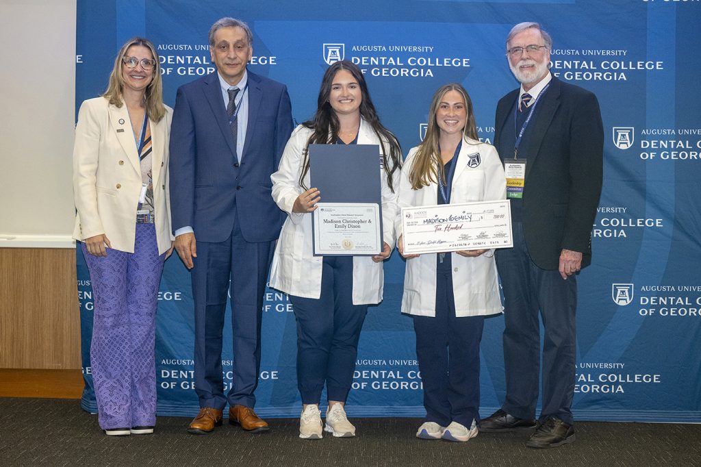 Winners hold award next to presenters.